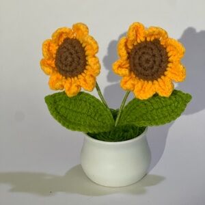 Two mini crocheted sunflowers in plastic pot.